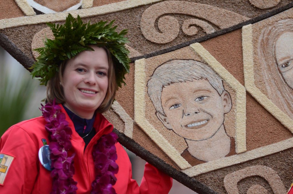 Katy Portell standing with the mosaic of her donor, PJ, on the Donate Life float at the Rose Bowl Parade. Photo Credit: Katy Portell Facebook