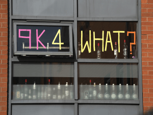 Student decorates door window with the words '9K for what?'