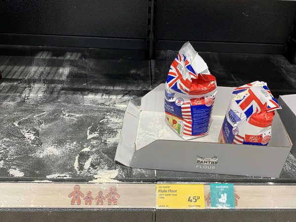 A shelf in Aldi that shows that only two ripped packs of plain flour are left.