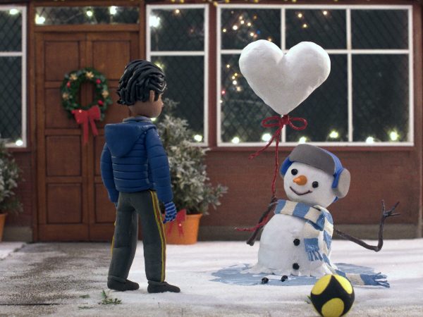 A snowman passes a balloon in the shape of a love heart to a child