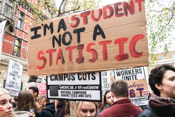 A student at a protest holding a sign that says 'I'm a student not a statistic'.
