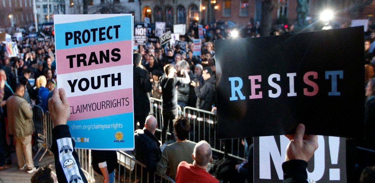 A participant holds signs from a stoop next door to the Stonewall National Monument during a rally in support of transgender youth, in New York. Several hundred demonstrators shouted "Trump is a fascist, drive him out" at the Manhattan rally, in which supporters spoke out against President Donald Trump's decision to roll back a federal rule saying public schools had to allow transgender students to use the bathrooms and locker rooms of their chosen gender identity 23 Feb 2017