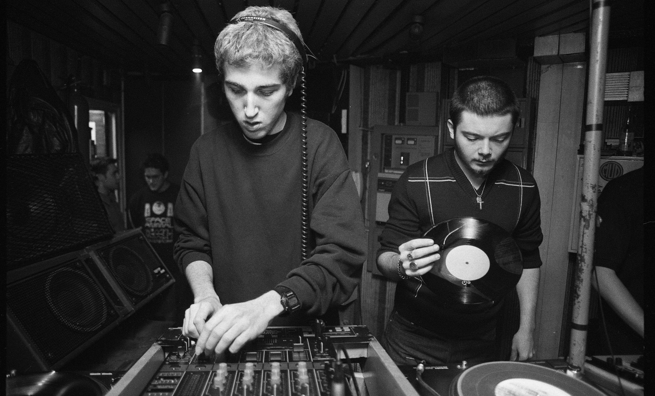 Two men using DJ equipment.