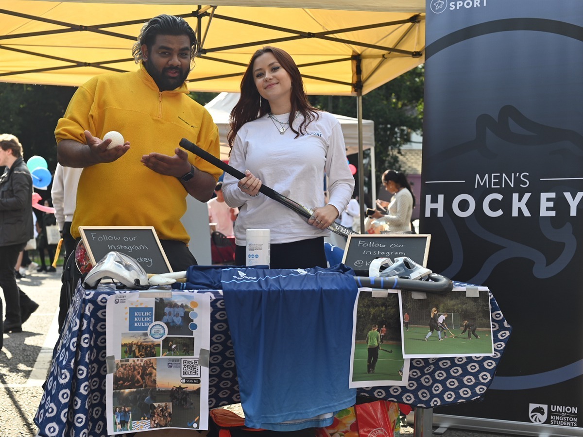 Hockey captain and representative posing with a hockey stick and ball at their stall