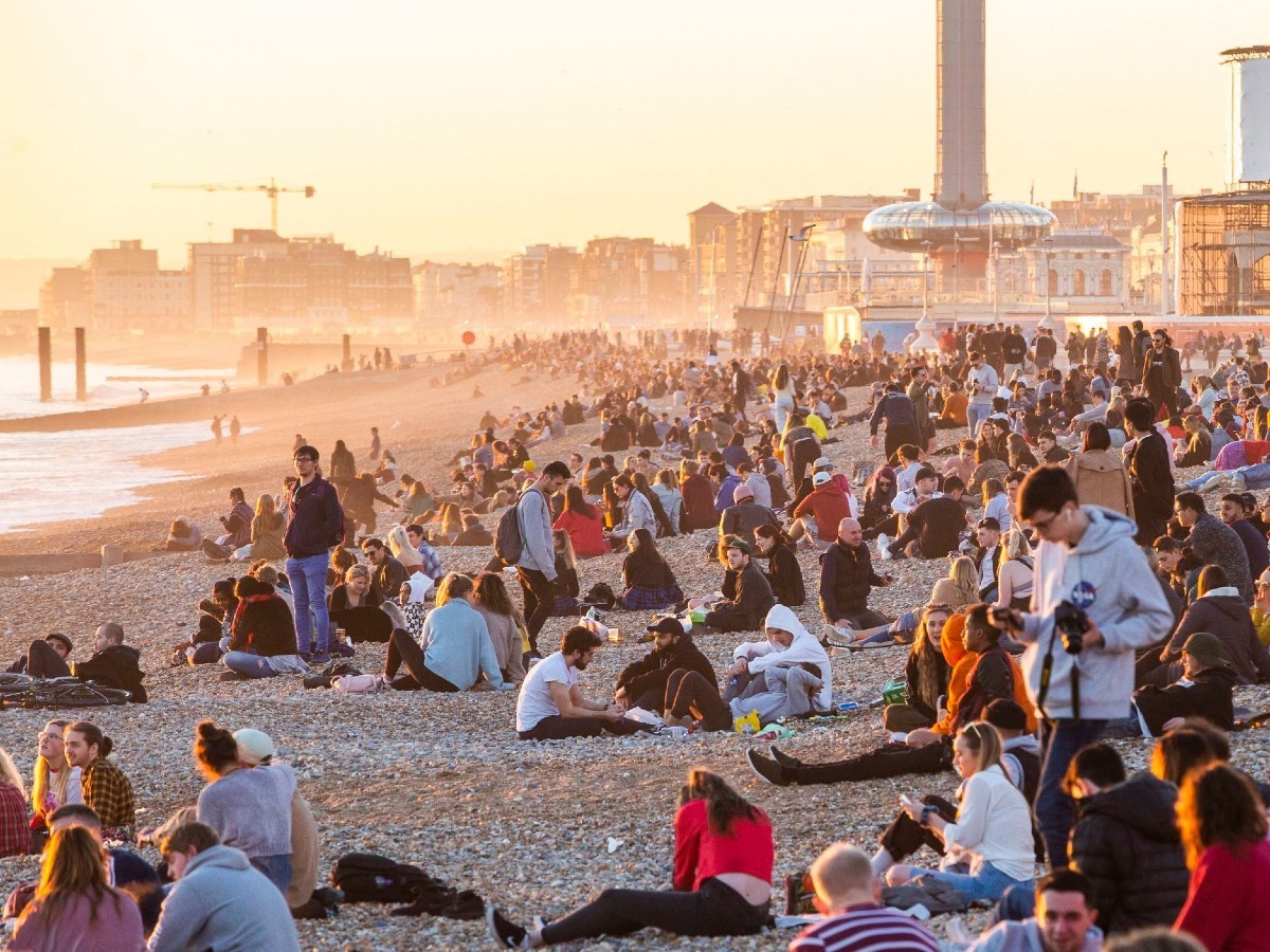 A large number of people sitting on Brighton beach
