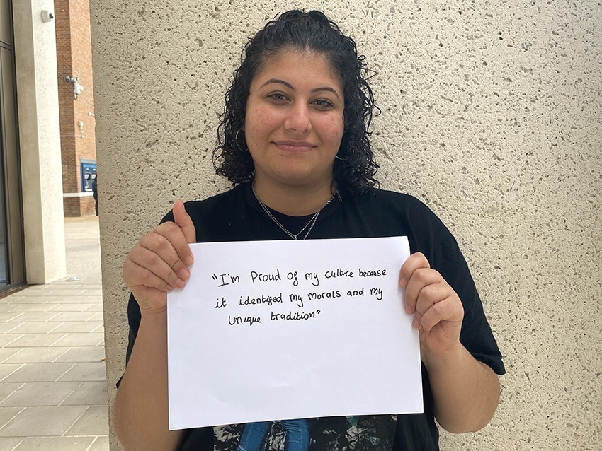 Student holding up a sign saying: "I am proud of my culture because it identified my morals and my unique tradition."