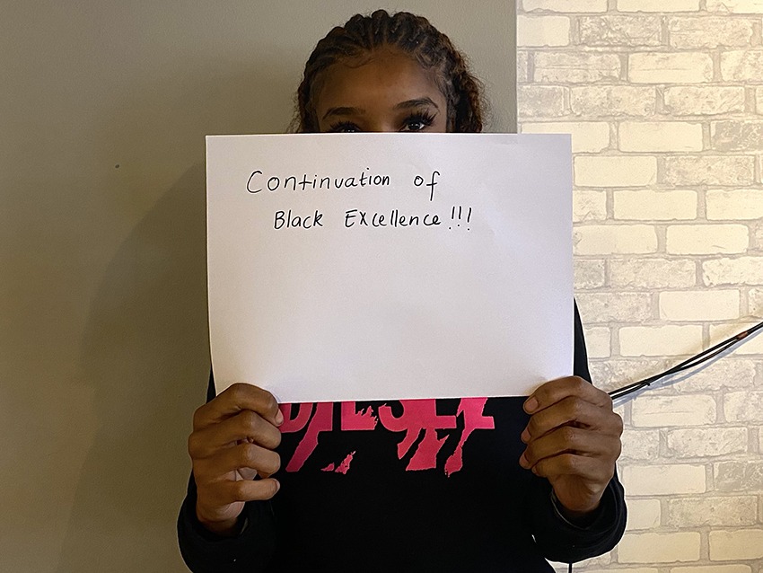 Student holding up a sign saying the continuation of black excellence.