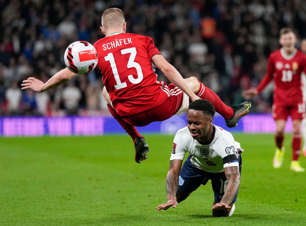 Hungary's Andras Schafer, top, collides with England's Raheem Sterling as they compete for the ball during the World Cup 2022 group I qualifying soccer match between England and Hungary at Wembley stadium in London