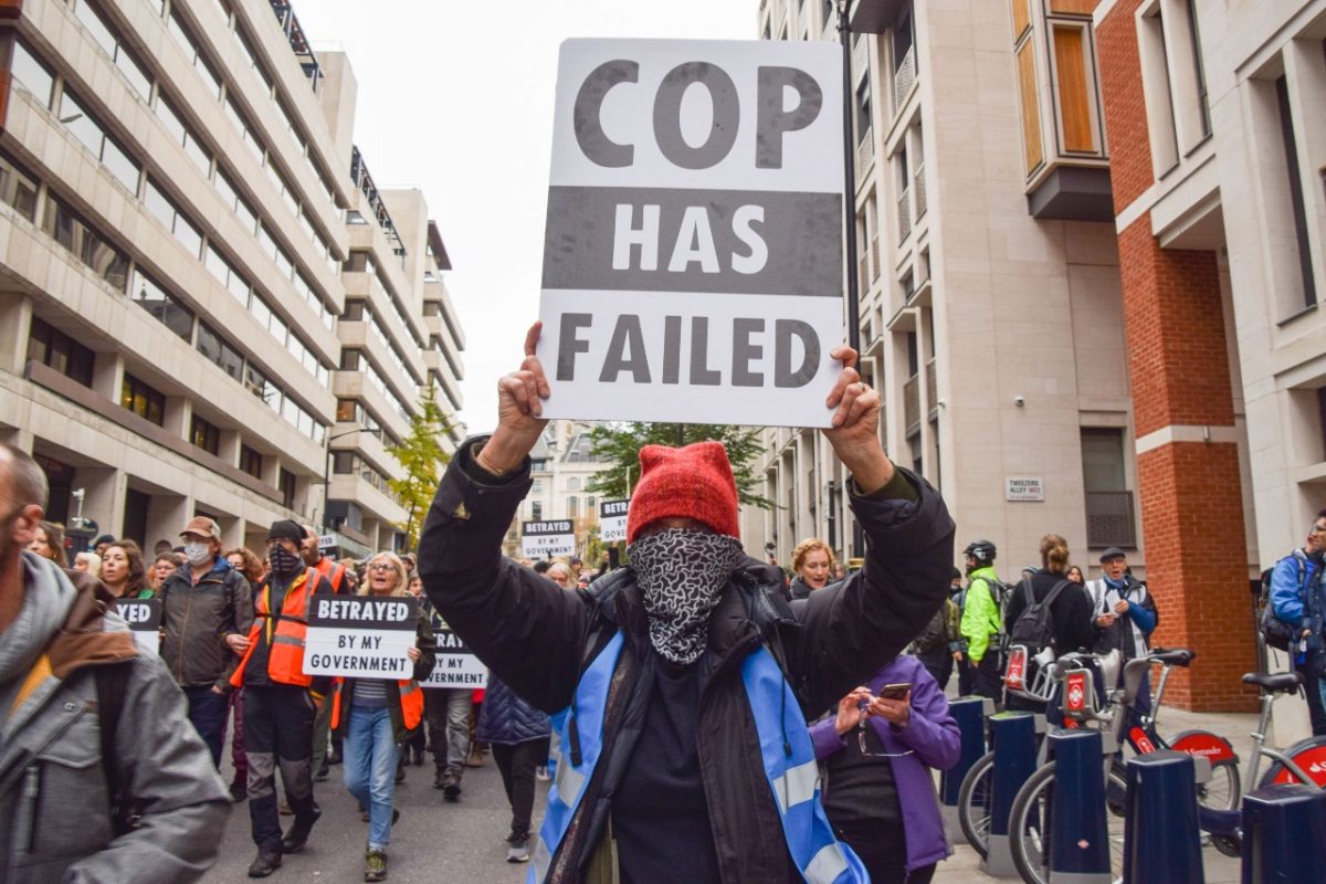 Person is holding 'COP has failed us' placard at a protest