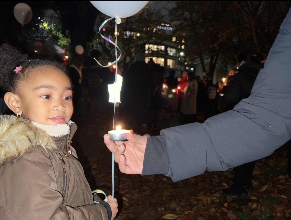 Young girl holding balloon and looking at a candle. 