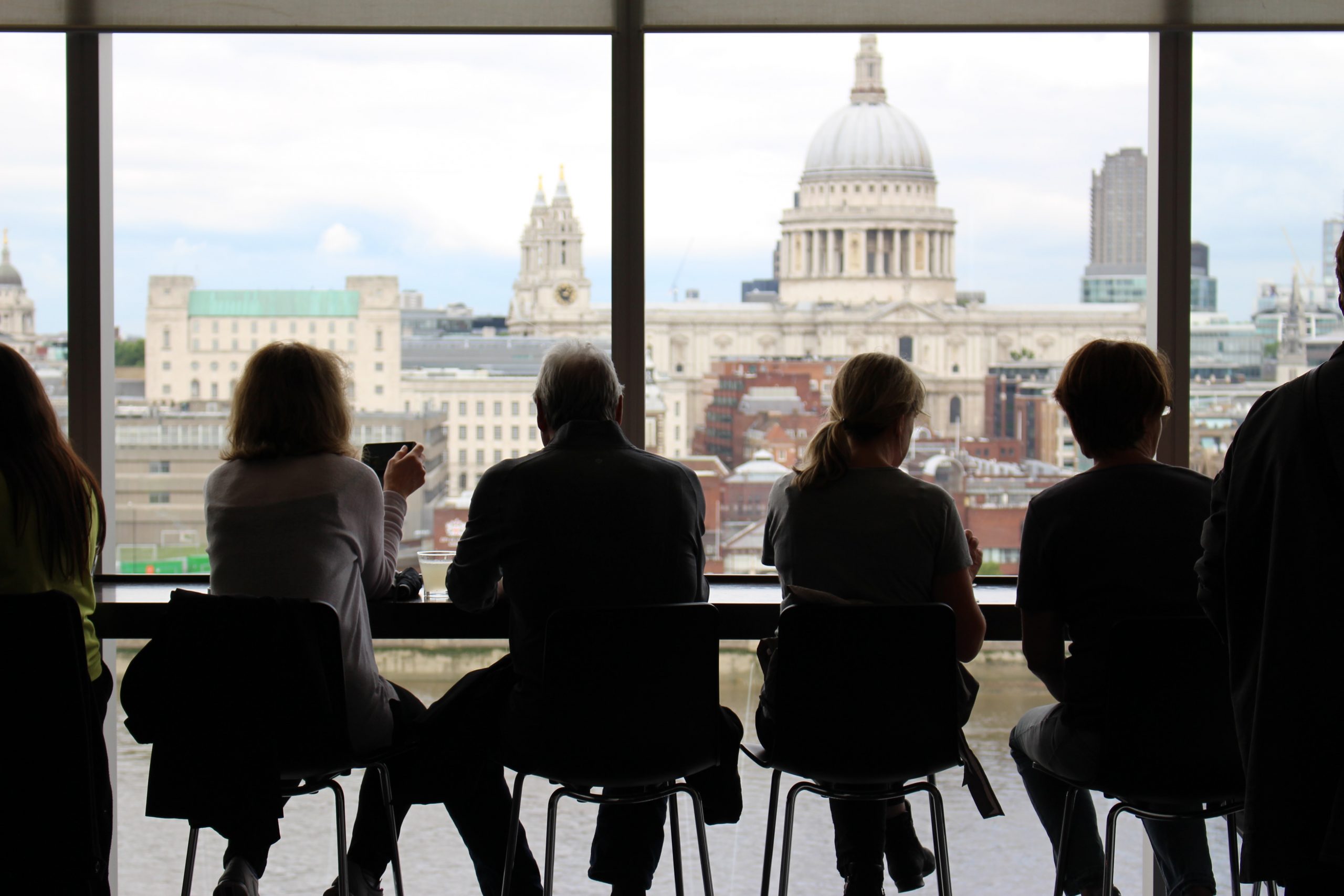 People sitting on a table watching the London skyline.