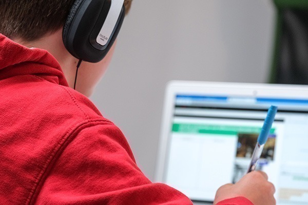 boy in red jumper studying on laptop