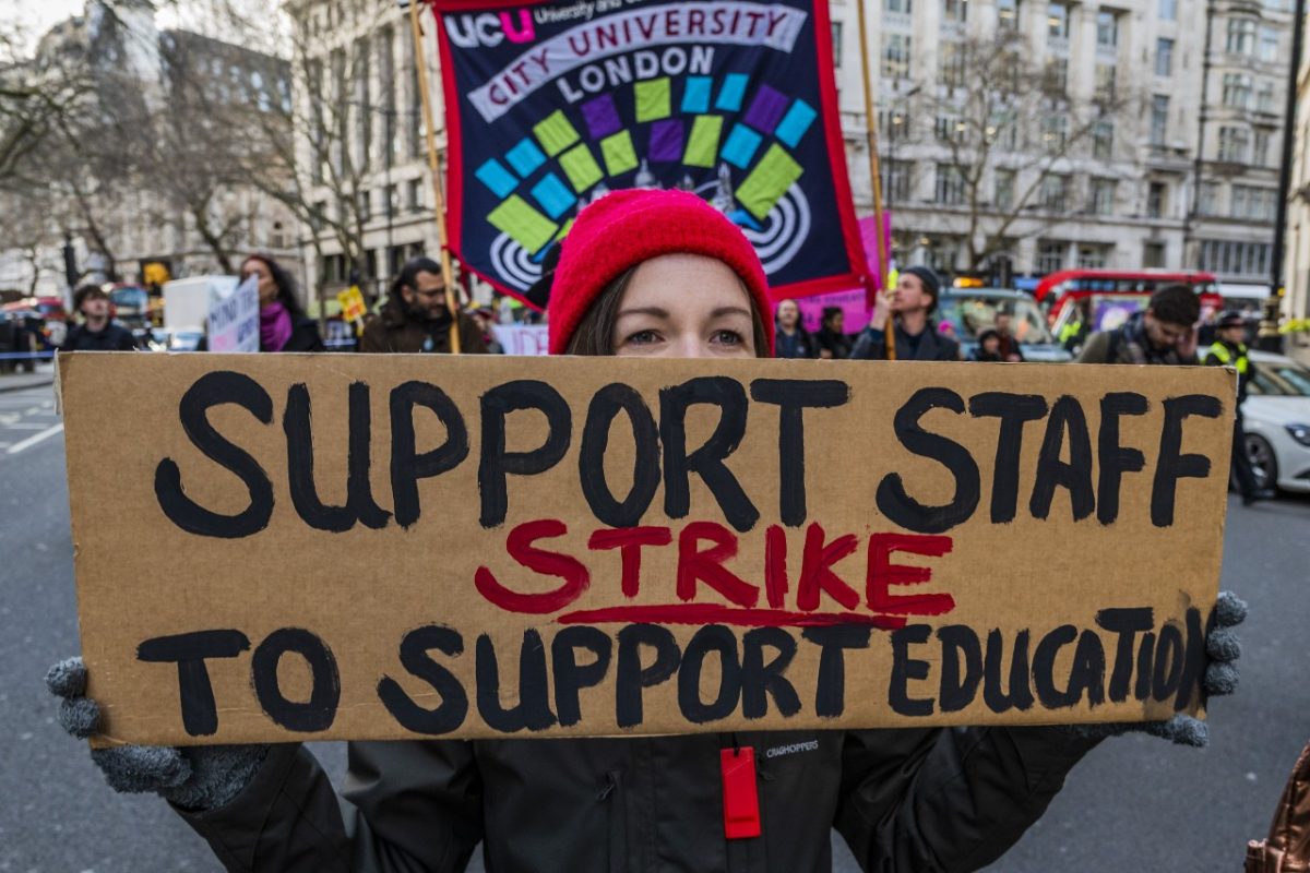 Student holding a protest sign saying 'support staff strike to support education.' 