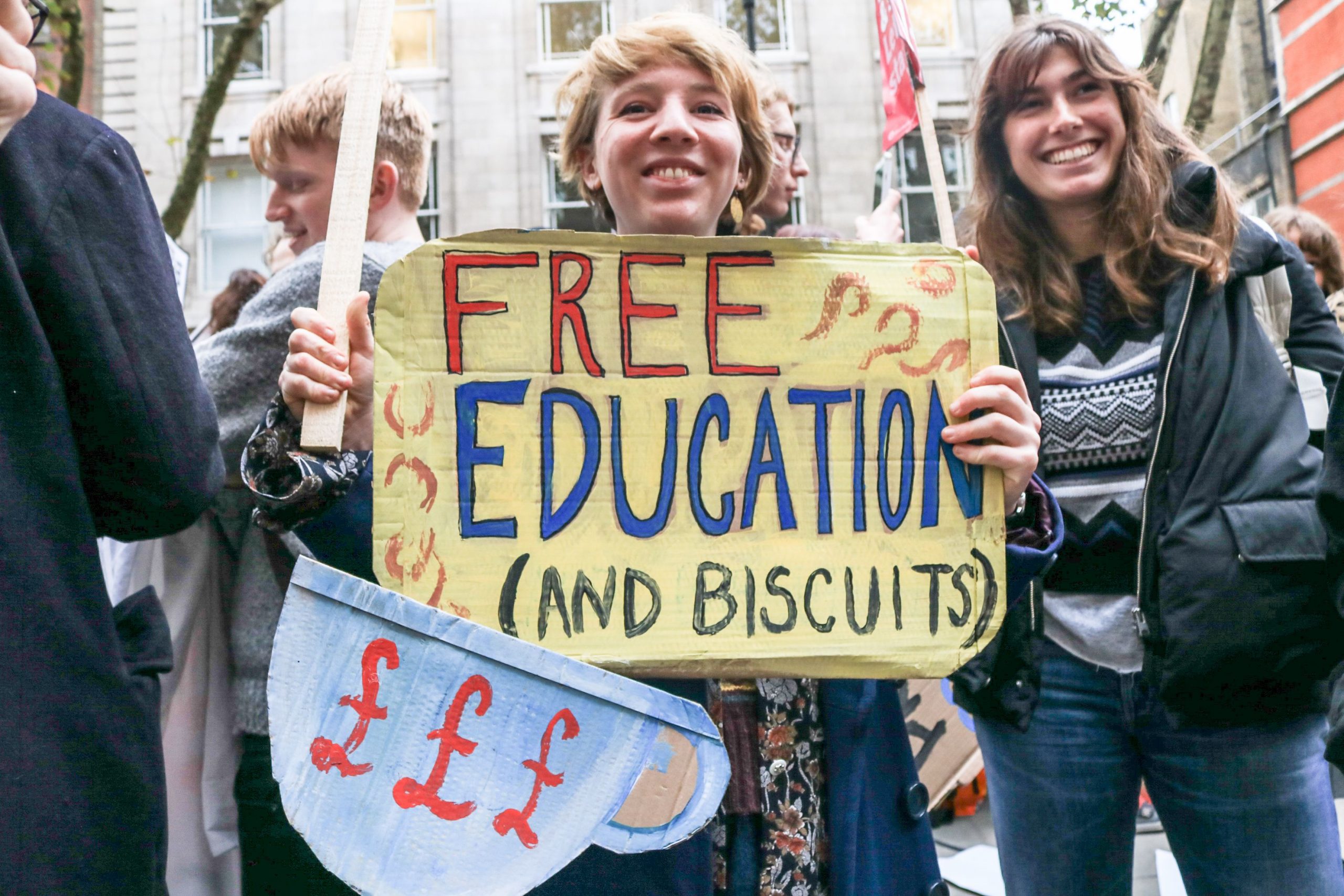 Students protesting holding a sign reading Free education (and biscuits)