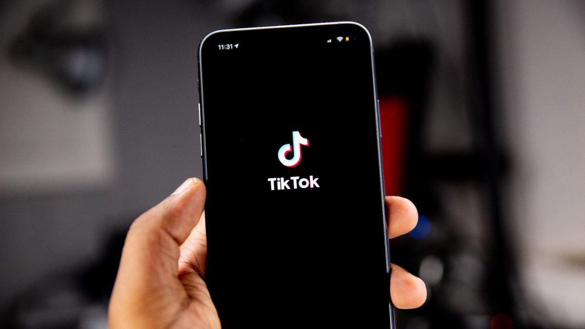 Hand holding a phone showing TikTok logo