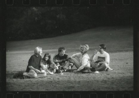 five students sitting on the grass
