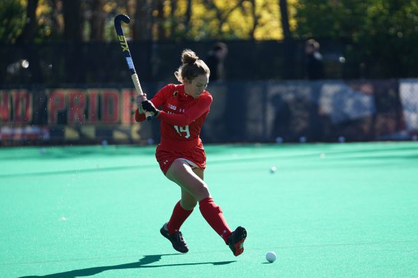 Hockey player in red outfit ready to hit the ball