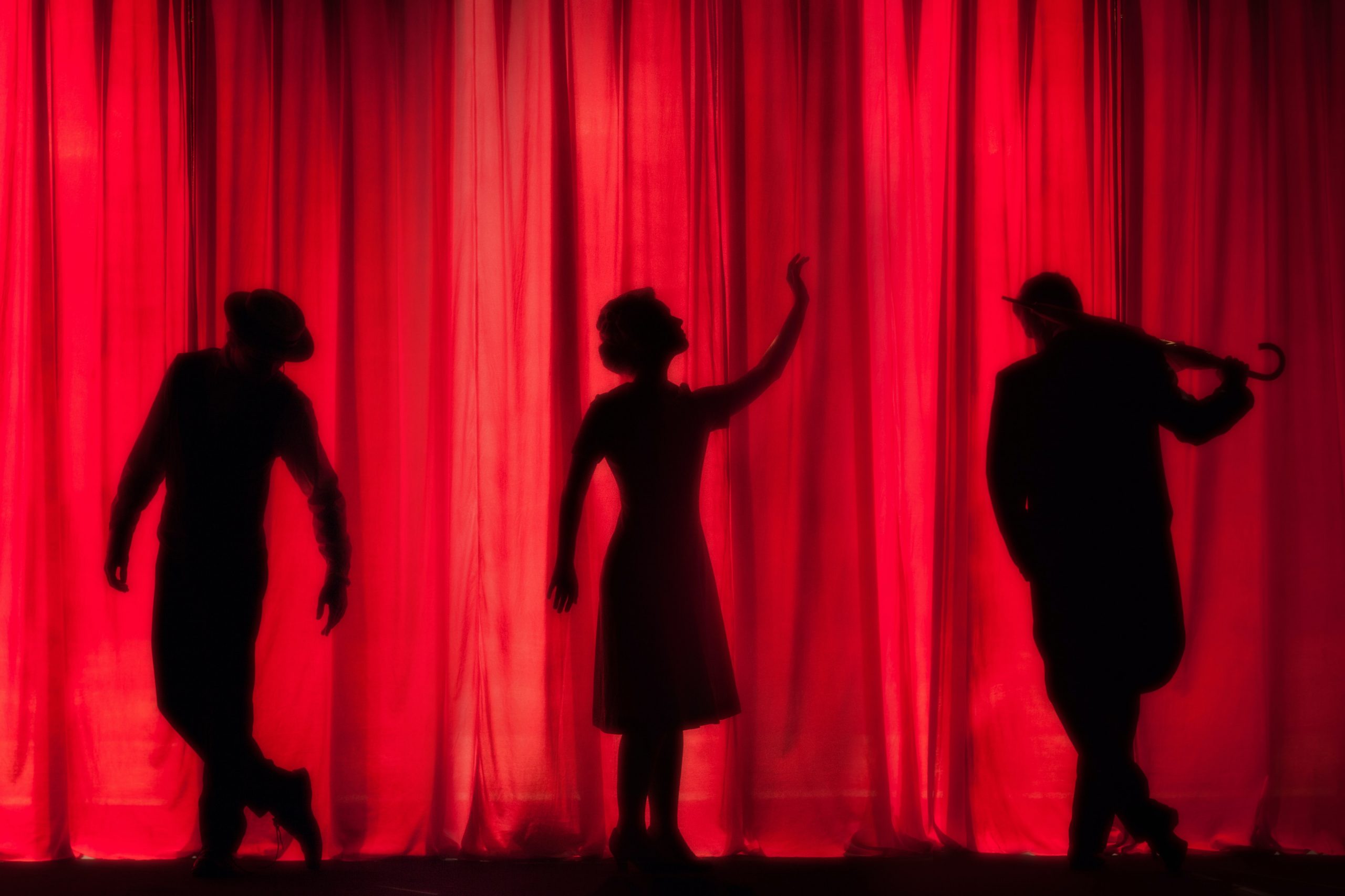 Three silhouettes standing on stage.