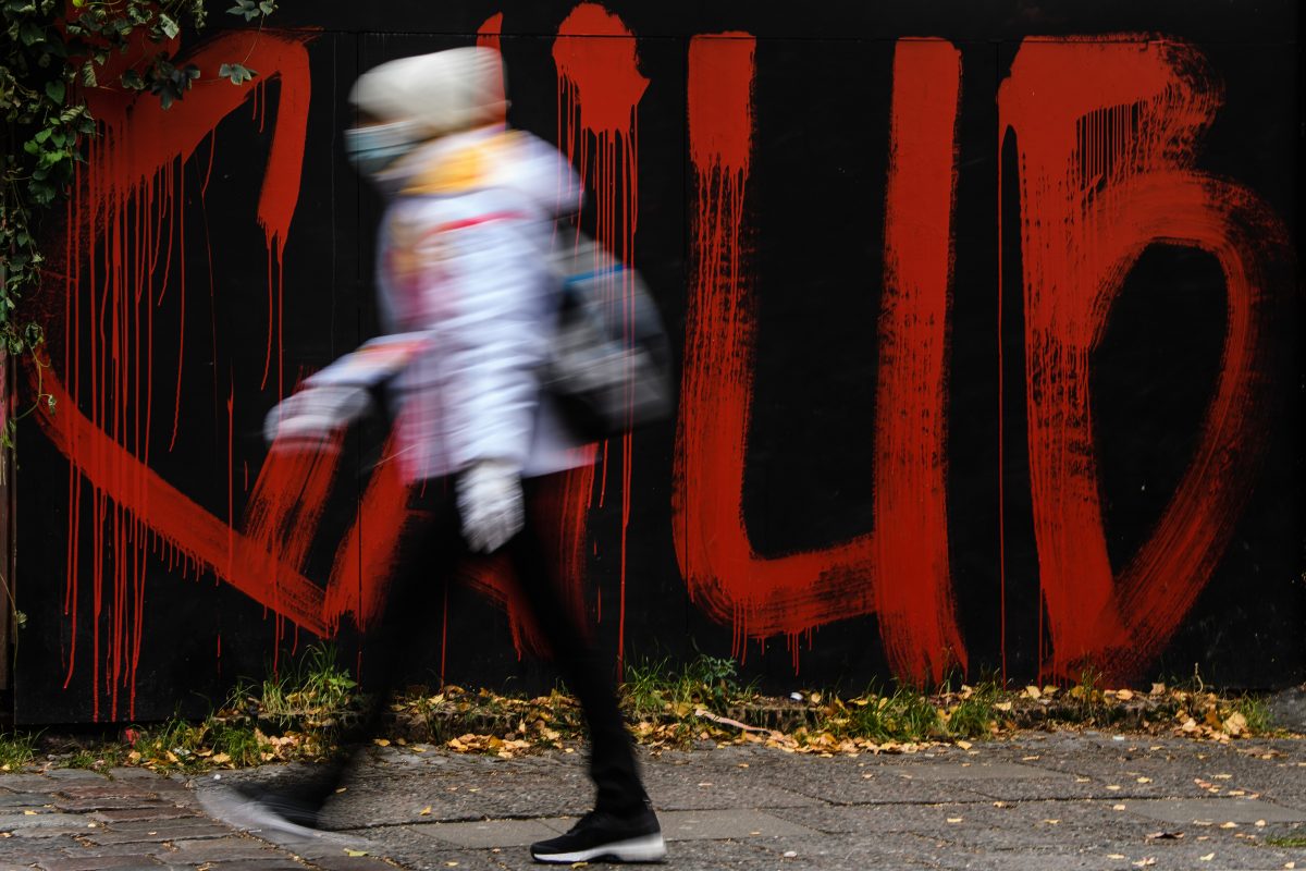 Person walking past graffittied wall
