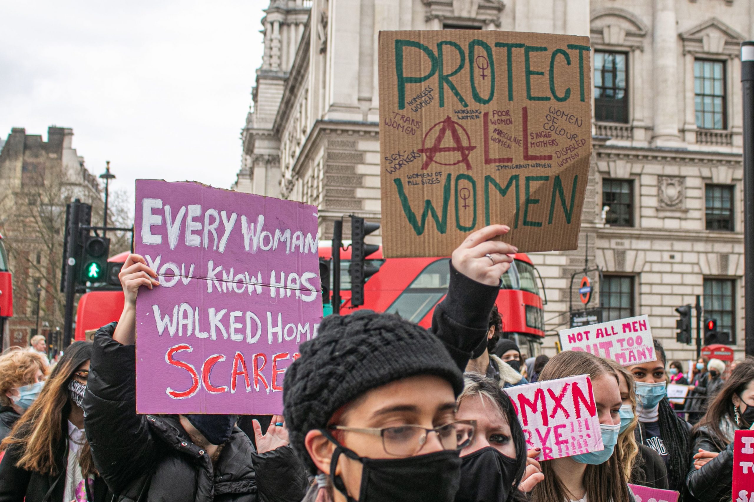 Protest signs reading "Every woman you know has walked home scared" and "Protect all women"