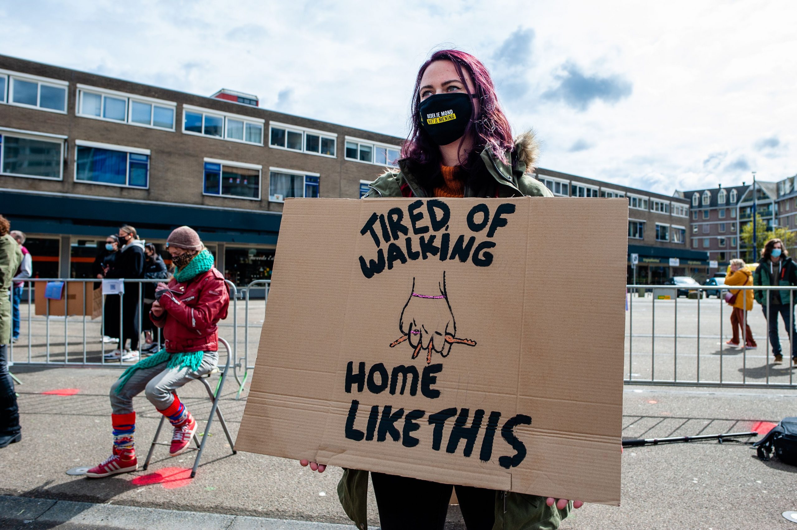 Protest sign reading "Tired of walking home like this" with a picture of a hand holding keys for protection.