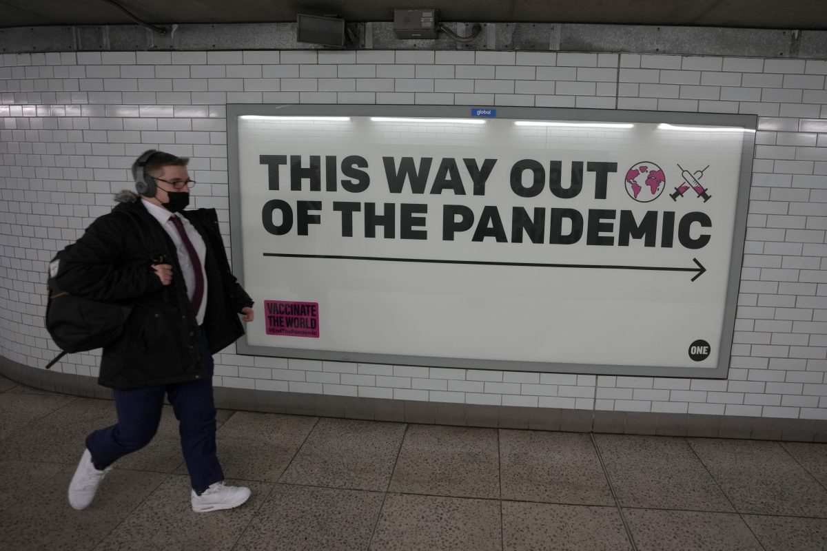 man walking next to sign saying this way out of the pandemic