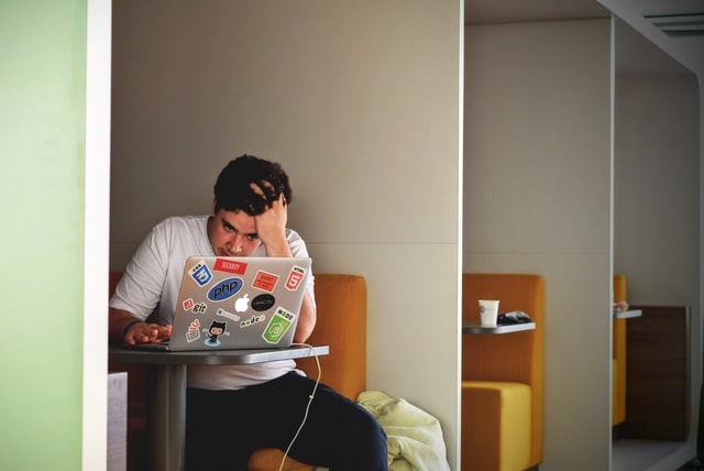 boy sitting over laptop hand in hair