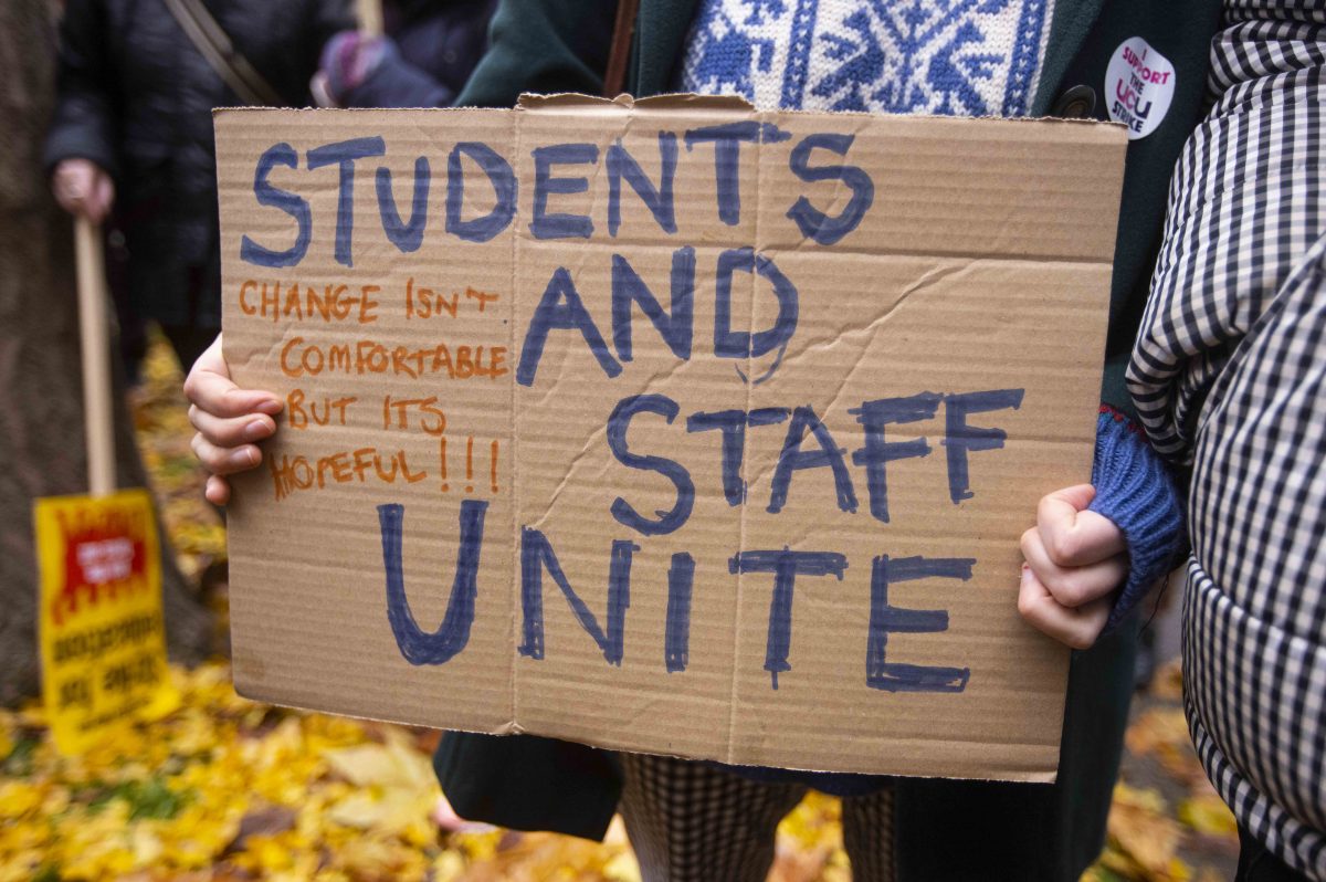 Protester holding a sign reading 'Student and staff unite' 'Change isn't comfortable but it's hopeful'