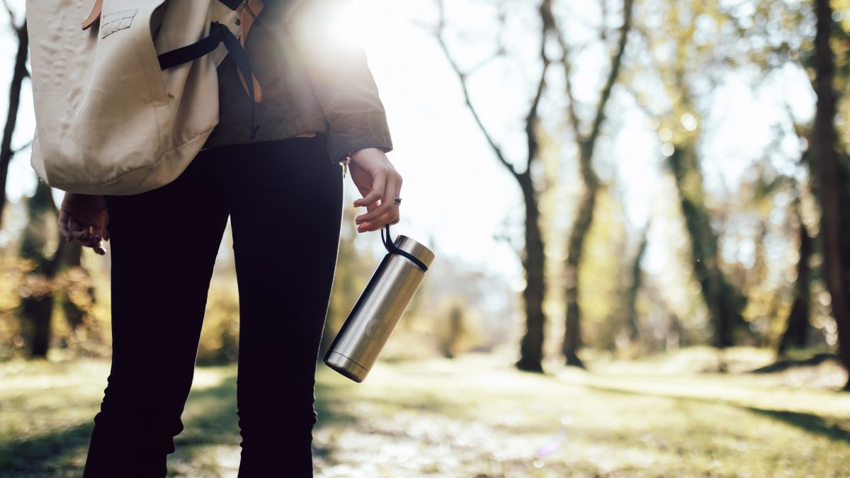 Person holding a stainless steel water bottle.