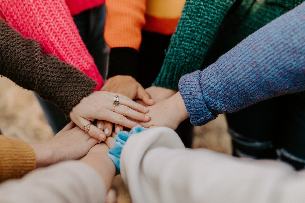 group of people putting their hands above one another 