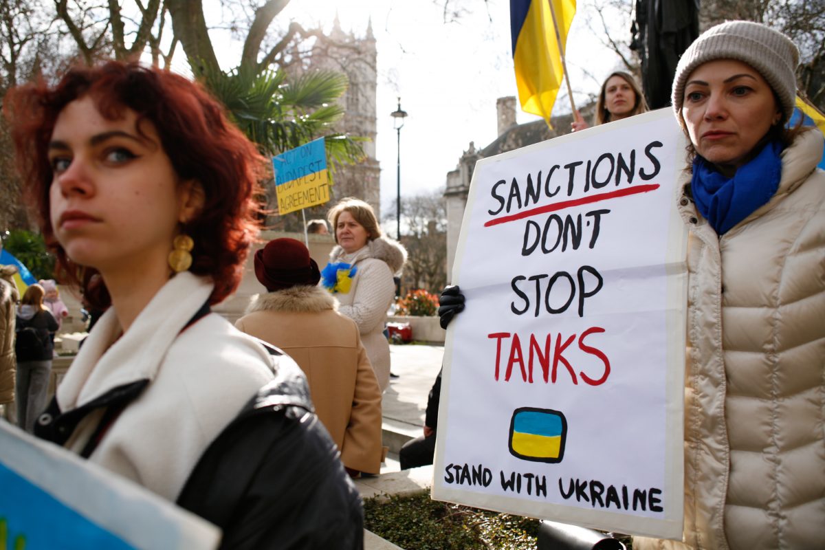 Protesters holding a banner reading 'sanctions don't stop tanks, stand with Ukraine'