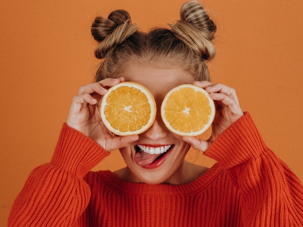 Girl holding slices of oranges over her eyes