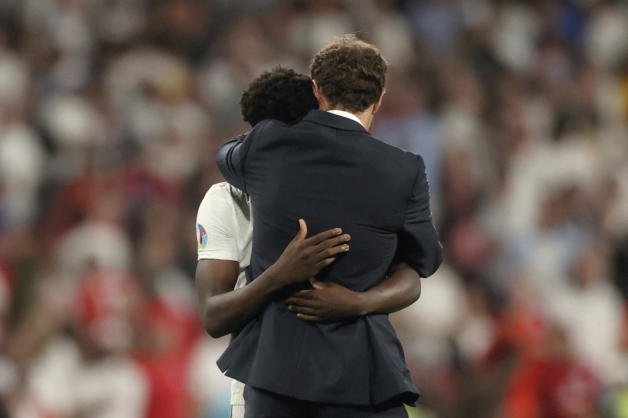 Blurred background, but an in focus shot of Gareth Southgate hugging Bukayo Saka