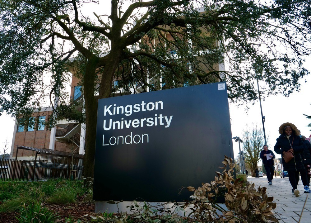 a sign saying kingston university next to a tree