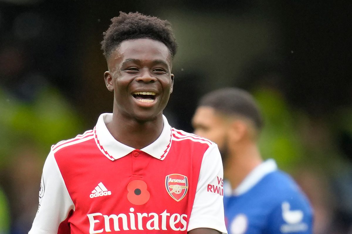 Saka smiling with the red Arsenal shirt and a red poppy sewn into it.