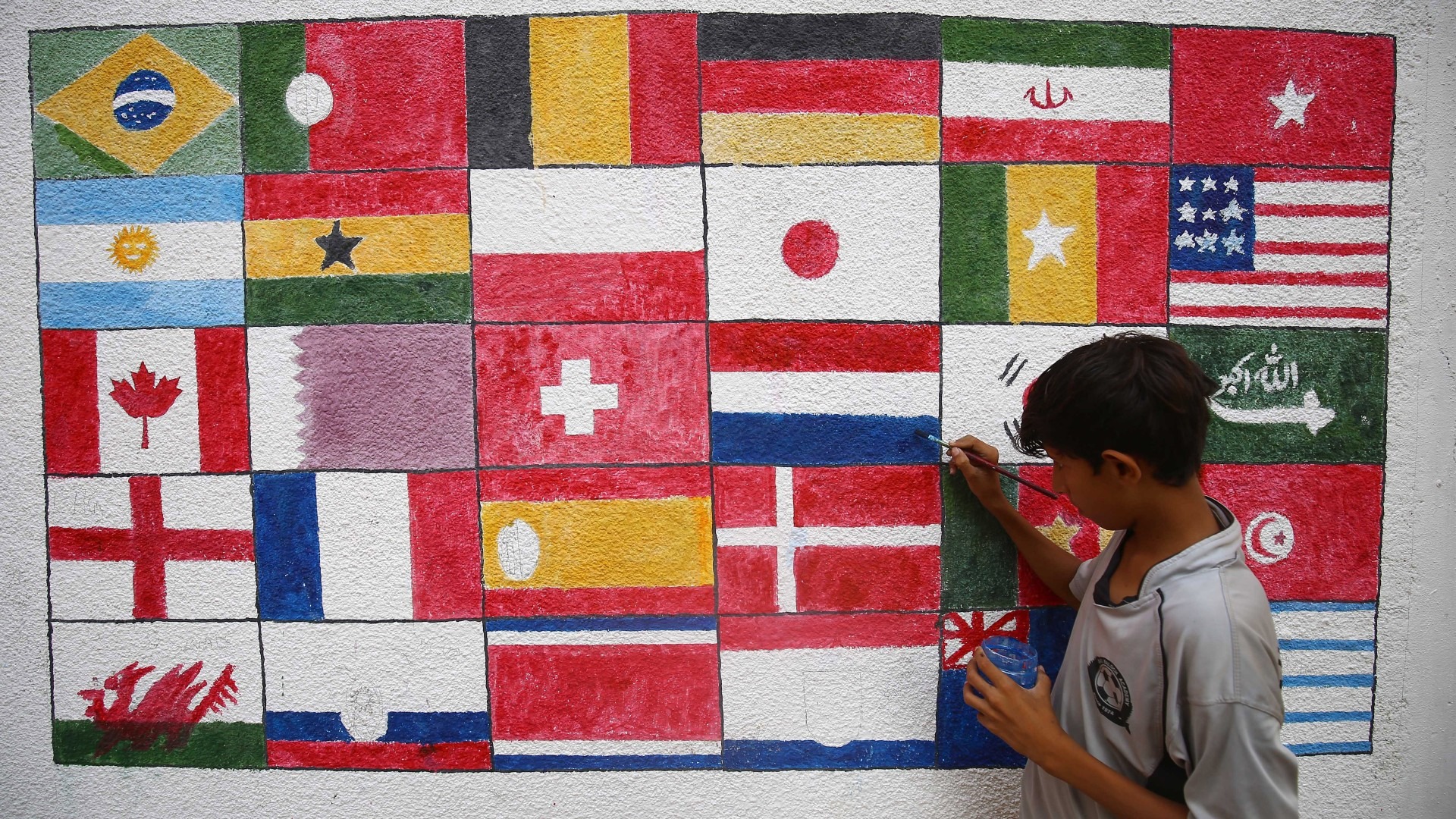 An artist paints flags of participating nations on a wall ahead of the FIFA World Cup Qatar 2022 in Karachi, Pakistan