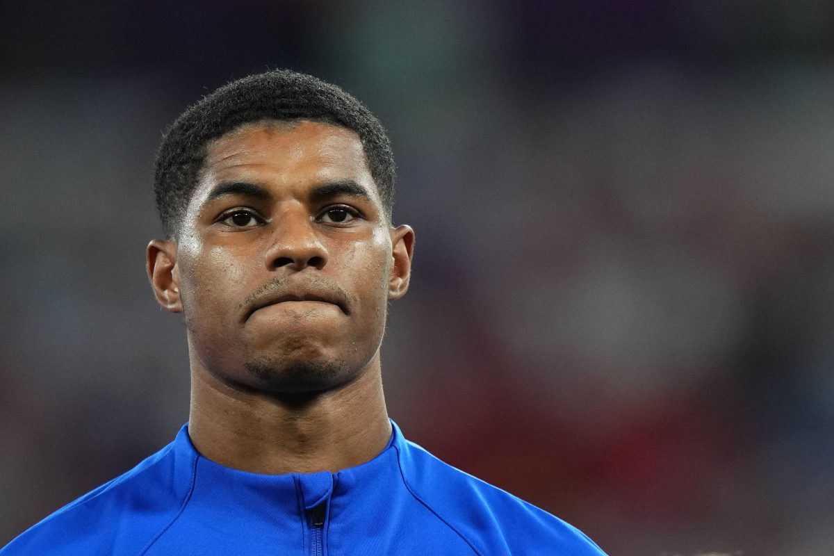 Close up shot of Marcus Rashford wearing a blue sweatshirt. The background is blurred in order to focus on him.