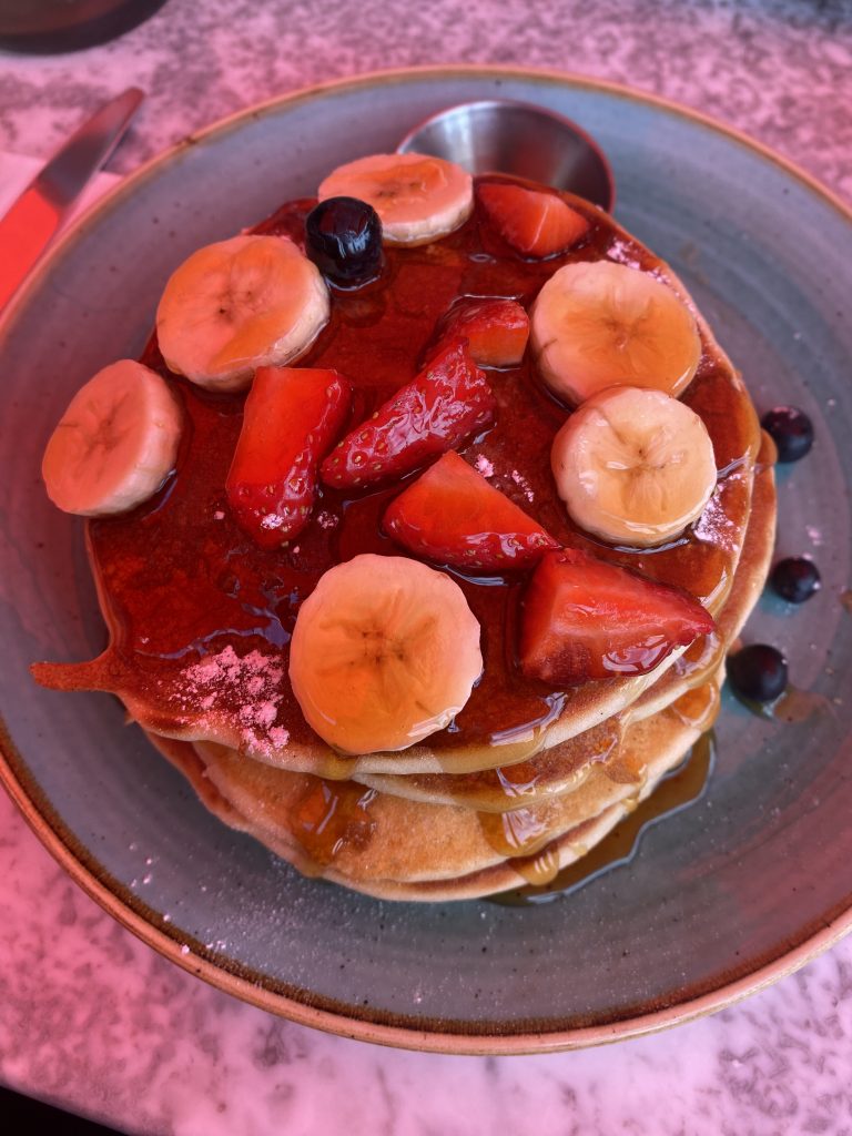 pancake stack topped with fruit and syrup