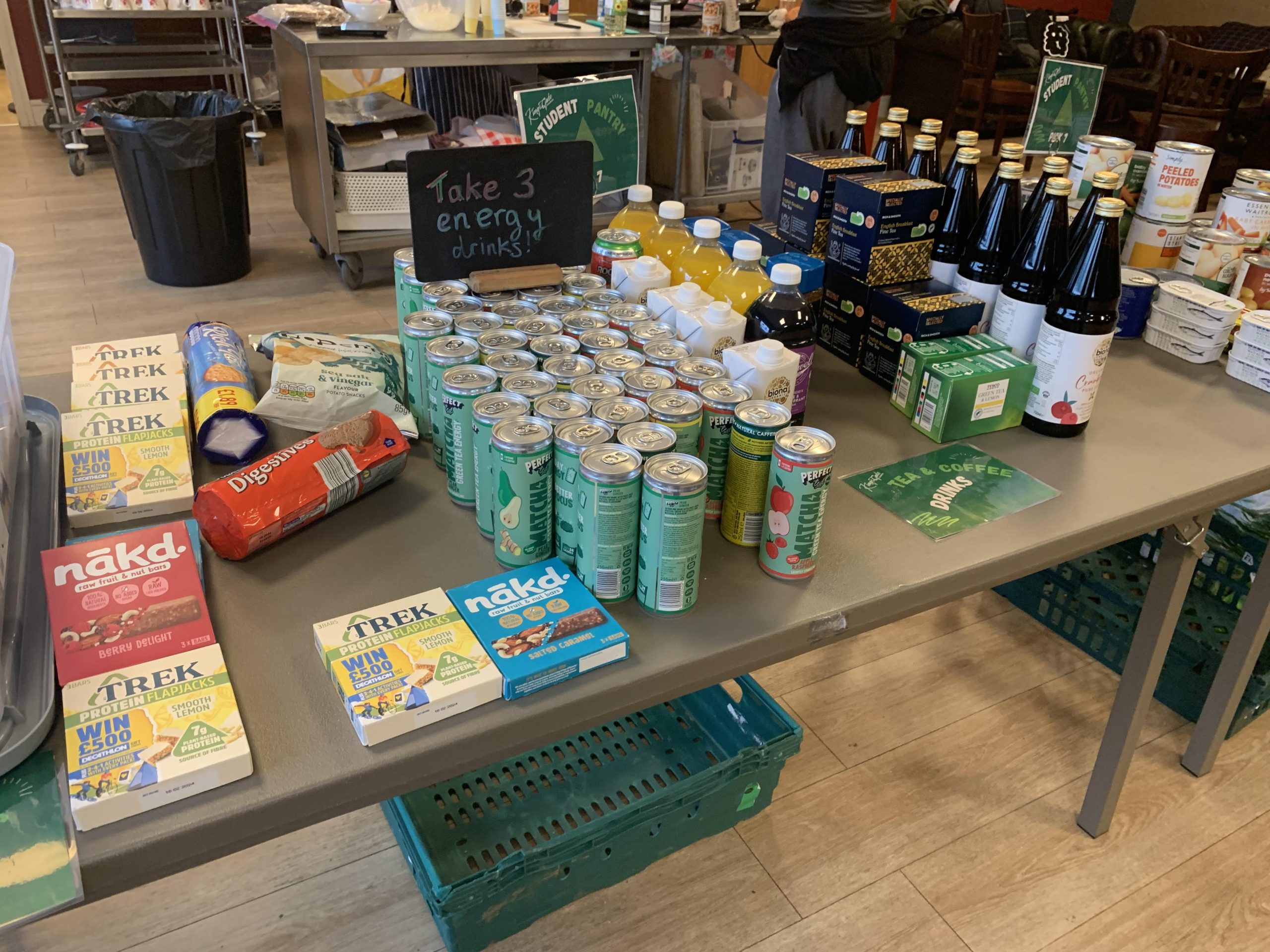 A table at a food pantry with various breakfast items, drinks, and canned foods visible.