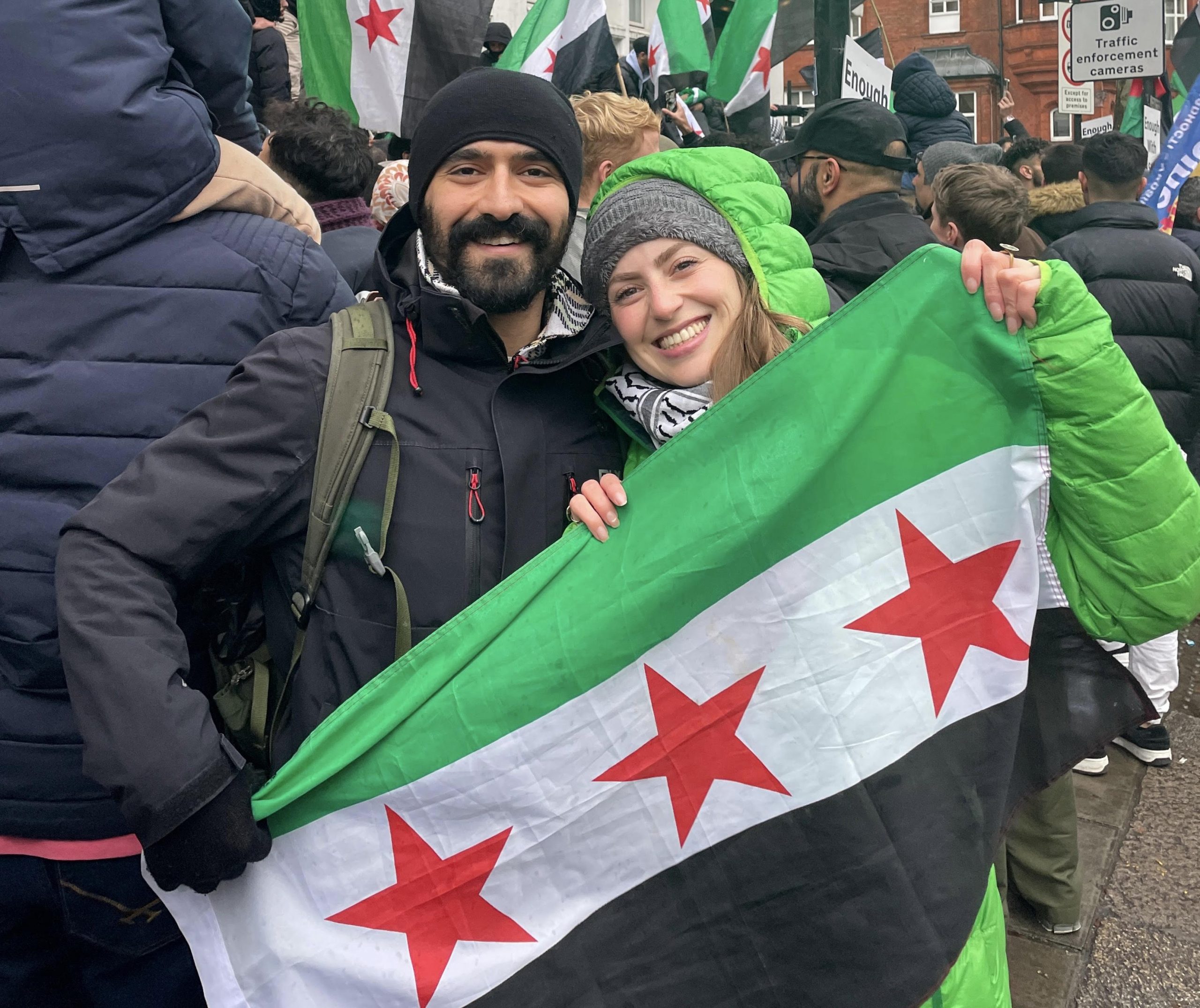 Two people hold the Syrian flag at a demonstration celebrating the collpase of the Assad regime.